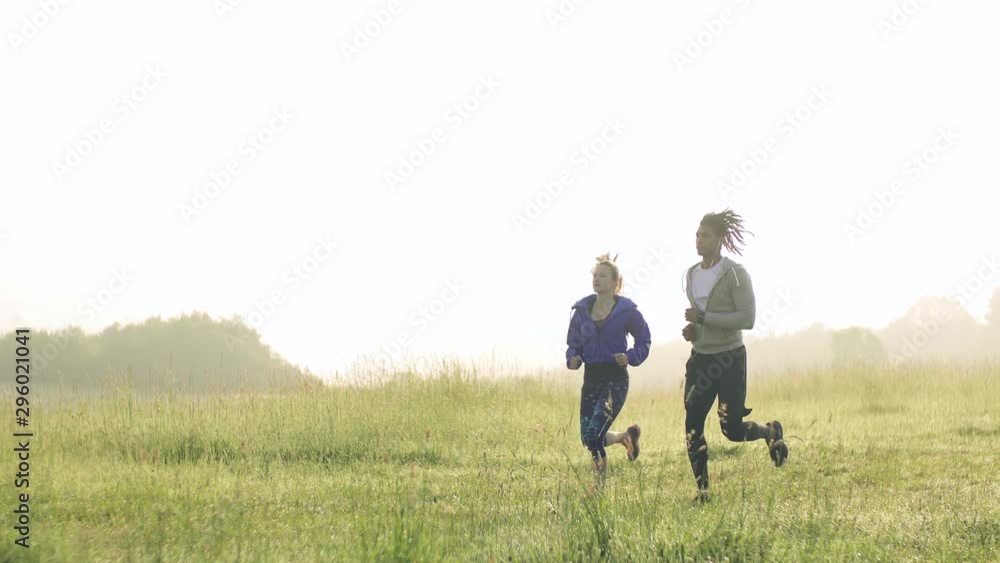 Young couple running on meadow outdoors in nature, in foggy morning. Young couple running on meadow outdoors in nature, in foggy morning.