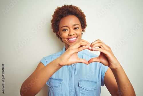 Young beautiful african american woman with afro hair over isolated background smiling in love showing heart symbol and shape with hands. Romantic concept.