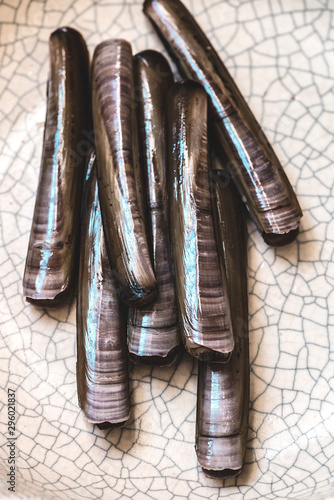 Fresh Razor Clams (Cannolicchi) on a rustic ceramic background. Rare clams of Mediterranean cuisine, fish market photo