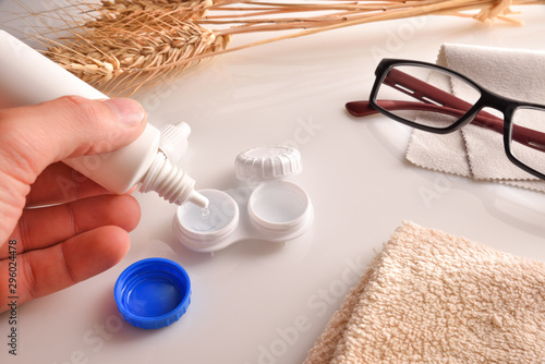 Canvastavla Hand filling a contact lens case with a solution bottle