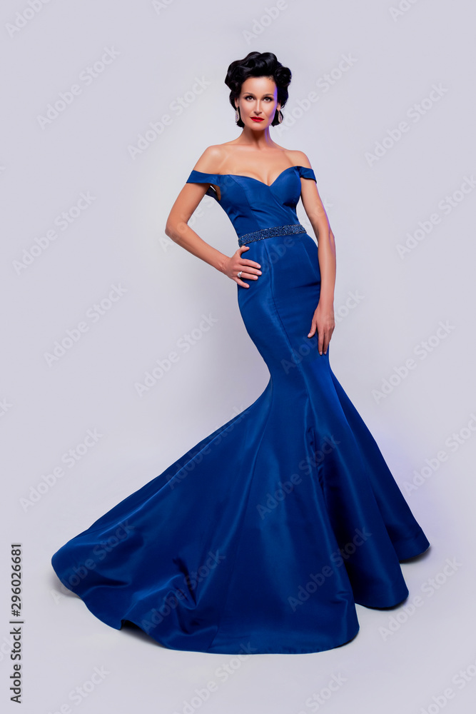 Beautiful attractive woman posing in full length and wears blue studio dresses. fashionable brunette woman in a luxurious blue fitted dress. elegant brunette woman with beautiful makeup and hairstyle Beautiful attractive woman posing in full length and wears blue studio dresses. fashionable brunette woman in a luxurious blue fitted dress. elegant brunette woman with beautiful makeup and hairstyle
