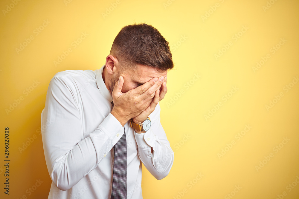 Young handsome business man wearing elegant white shirt over yellow isolated background with sad expression covering face with hands while crying. Depression concept. Young handsome business man wearing elegant white shirt over yellow isolated background with sad expression covering face with hands while crying. Depression concept.