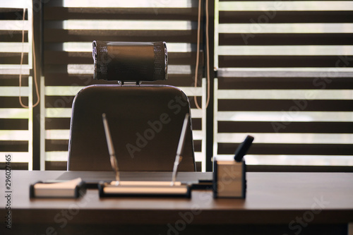 Business office workplace. Work place for chief, boss or other employees. Table and comfortable chair. Light through the half open blinds