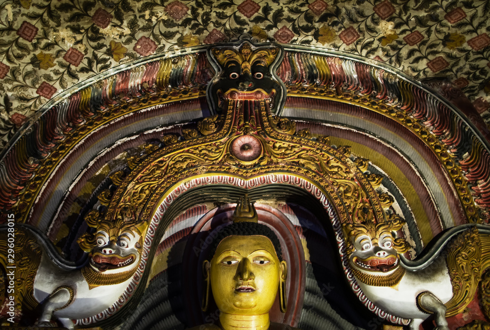 Fototapeta premium The head of the Buddha statue is framed by traditional Sri Lankan patterns of the first millennium AD, with snow lions on the side, and the head of a mystical animal on top. Temple Cave Complex in Dam