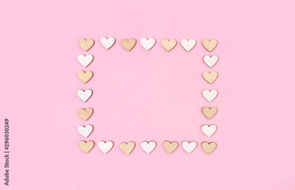 Frame made from wooden hearts on pastel pink background