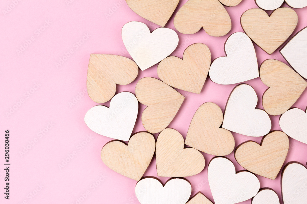 Creative holiday background made from wooden hearts on pastel pink backdrop Creative holiday background made from wooden hearts on pastel pink backdrop