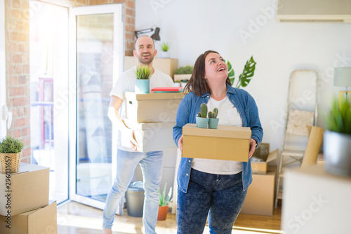 Young couple moving to a new home, smiling happy holding cardboard boxes