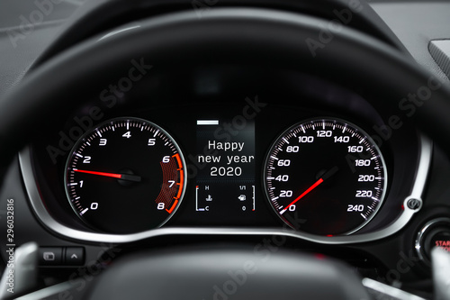 Close up Instrument automobile panel with Odometer, speedometer, tachometer, fuel level, which says Happy New Year 2020. The concept of the new year and Christmas in the automotive field.