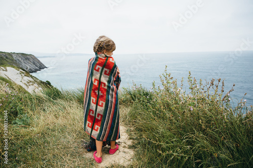 Little girl standing on the cliff of the mountain above the ocean in France photo