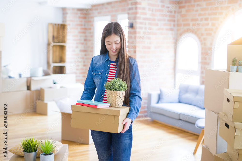 Beautiful asian young woman holding boxes, smiling happy moving to a new home Beautiful asian young woman holding boxes, smiling happy moving to a new home