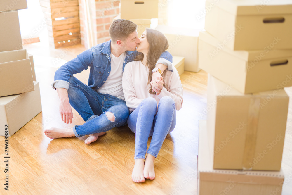 Young beautiful couple relaxing sitting on the floor around cardboard boxes at home, smiling happy moving to a new house Young beautiful couple relaxing sitting on the floor around cardboard boxes at home, smiling happy moving to a new house