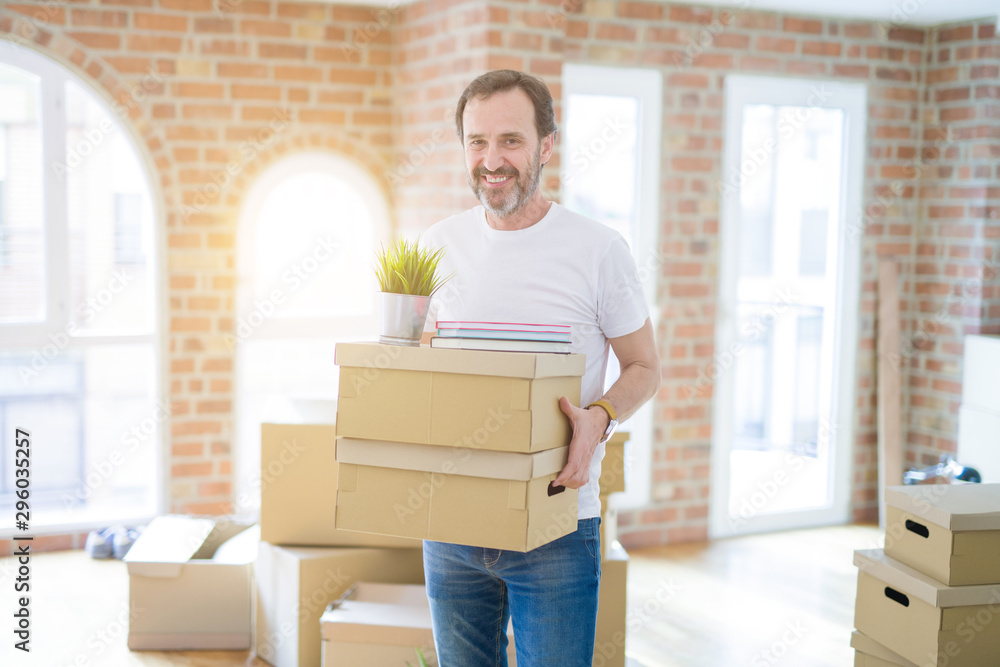 Handsome middle age senior man smiling happy moving to a new house, packing and holding cardboard boxes Handsome middle age senior man smiling happy moving to a new house, packing and holding cardboard boxes