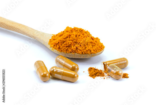 Turmeric powder in wooden spoon and tumeric capsules isolated on white background.  photo