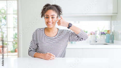 Beautiful african american woman with afro hair wearing casual striped sweater Pointing with hand finger to face and nose  smiling cheerful. Beauty concept