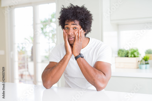 Young african american man wearing casual white t-shirt sitting at home Tired hands covering face, depression and sadness, upset and irritated for problem