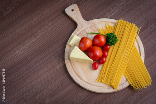 Spaghetti, tomatoes, broccoli and butter on a brown wooden floor