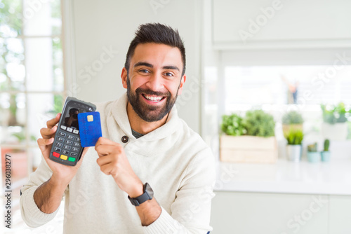 Business man smiling and holding point of sale terminal and credit card, contacless transaction photo