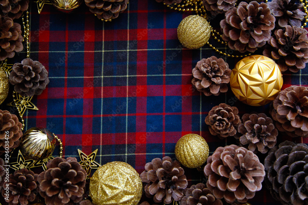 Frame of christmas decorations cones and golden balls on the blue-red plaid background. New Year Flat lays concept. Frame of christmas decorations cones and golden balls on the blue-red plaid background. New Year Flat lays concept.