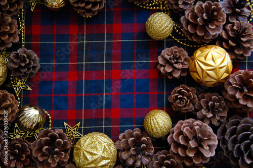 Frame of christmas decorations cones and golden balls on the blue-red plaid background. New Year Flat lays concept. 