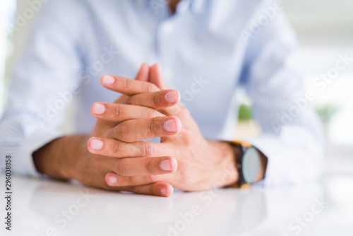 Close up of man with crossed hands over white table