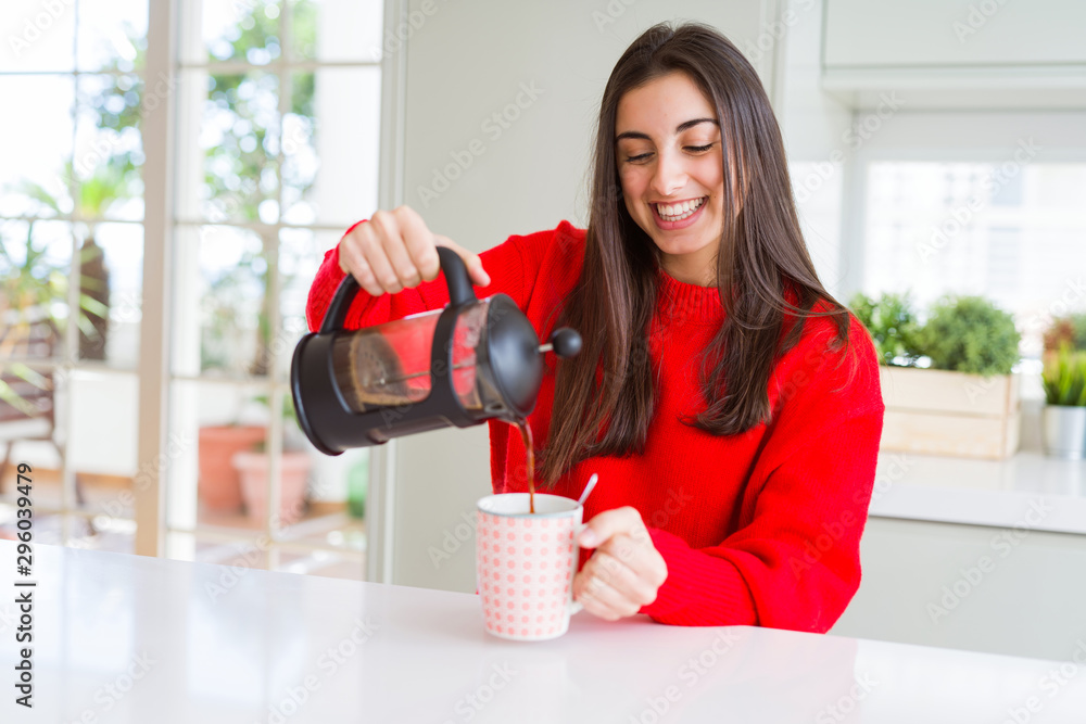 Young beautiful woman making morning coffee smiling, preparing a cup of latte for breakfast - obrazy, fototapety, plakaty 