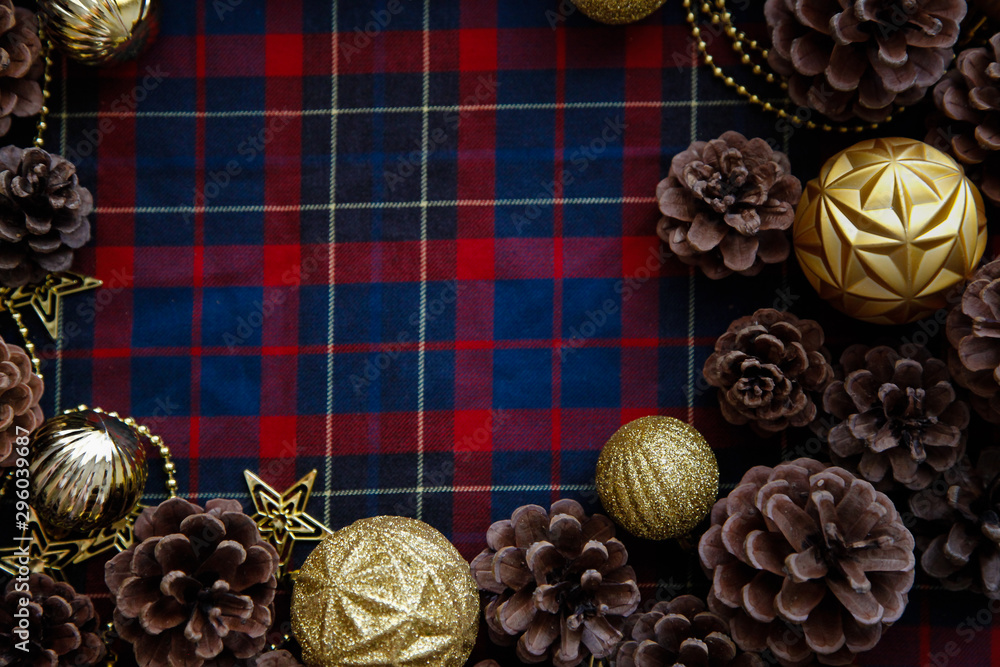 Frame of christmas decorations cones and golden balls on the blue-red plaid background. New Year Flat lays concept. Frame of christmas decorations cones and golden balls on the blue-red plaid background. New Year Flat lays concept.