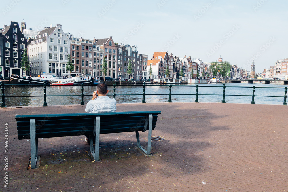 un touriste assis sur un banc à Amsterdam téléphonant