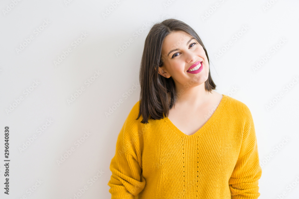 Obraz premium Beautiful brunette young woman smiling confident and cheerful over isolated white background wearing casual yellow sweater