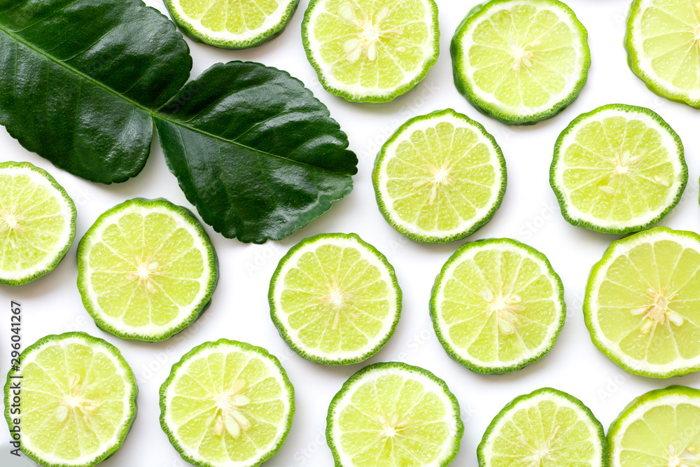 Fresh slices of bergamot fruits or kaffir lime and green leaf isolated on white background. Top view. Flat lay. - obrazy, fototapety, plakaty 
