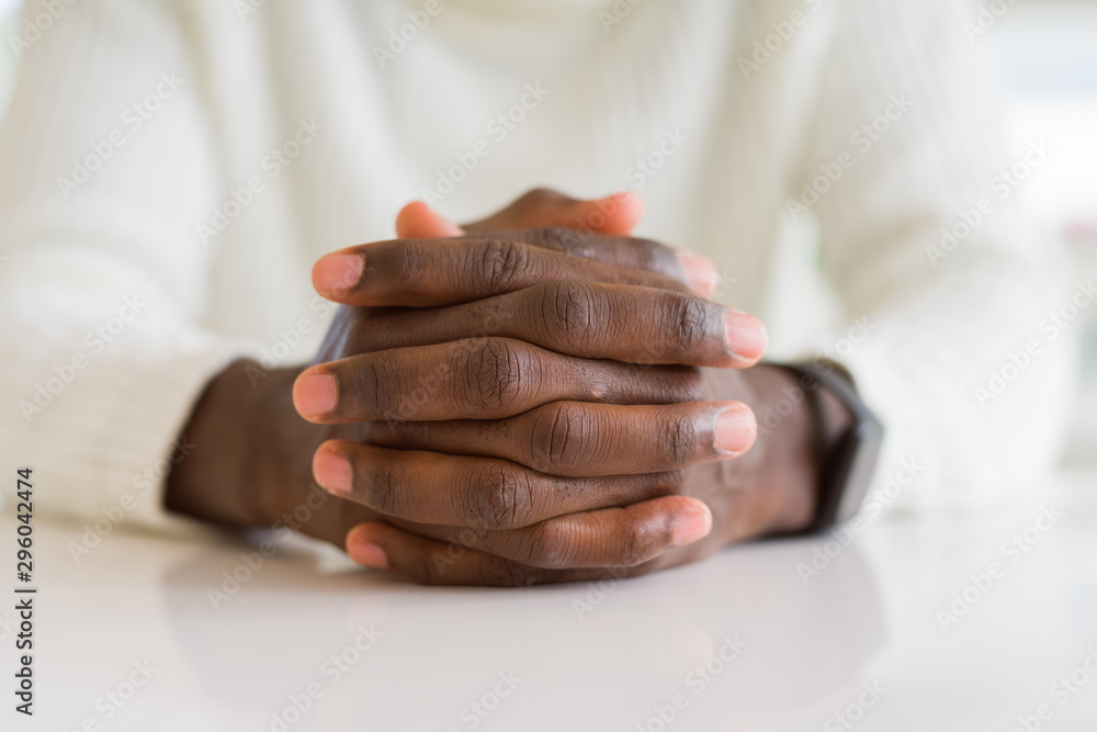 Close up of crossed hands of african man over table Close up of crossed hands of african man over table
