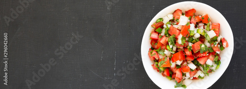 Pico de Gallo in a white bowl on a black background, top view. Overhead, from above, flat lay. Space for text.