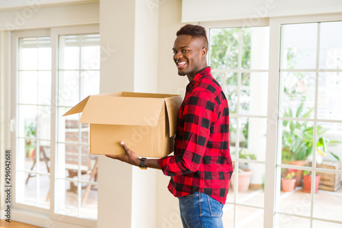Young african american man holding a carton box, packing cardboard delivery package at home