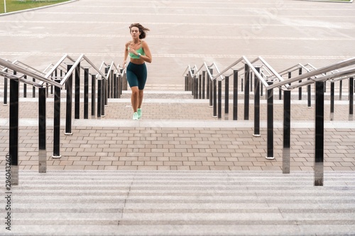 Young woman running alone up stairs outdoor.