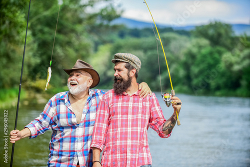 Family time. Activity and hobby. Fishing freshwater lake pond river. Mature man with friend fishing. Summer vacation. Happy cheerful people. Fisherman with fishing rod. Bearded men catching fish