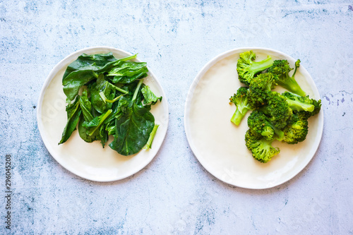 Fotografija Fresh green spinach leaves and broccoli on plate.