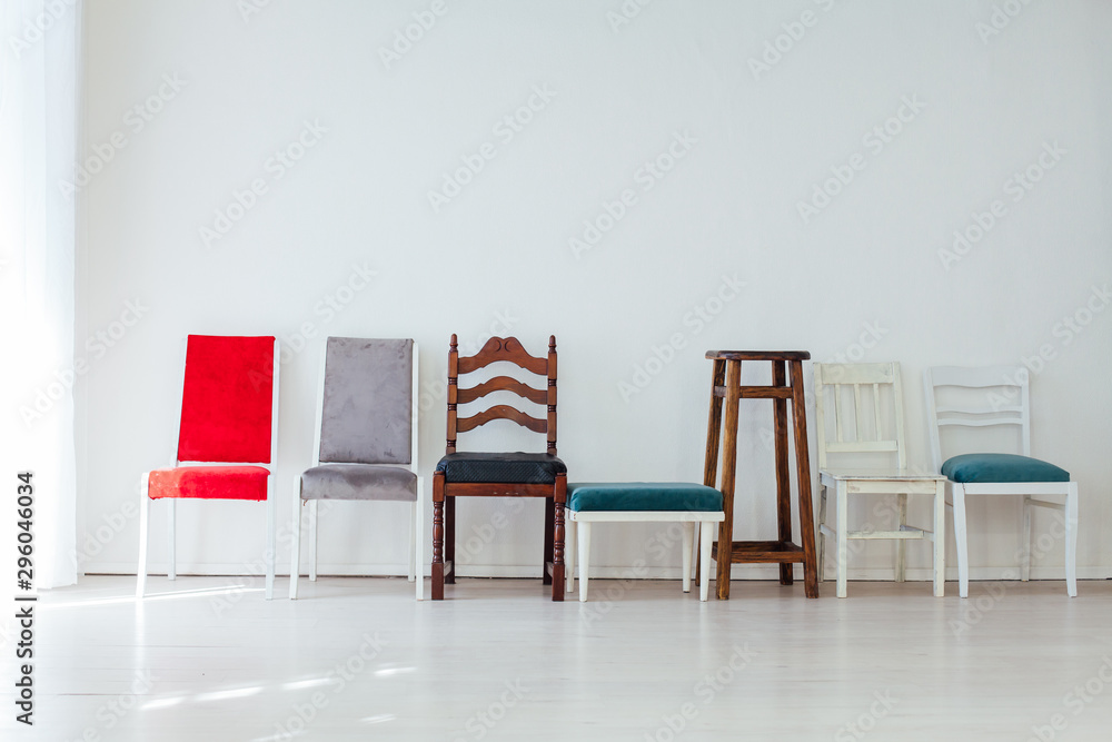 many multicolored chairs stand in the white room - obrazy, fototapety, plakaty 