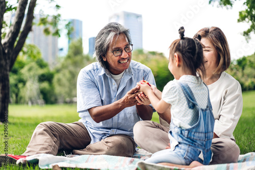 Portrait of happy grandfather with grandmother and little cute girl enjoy relax in summer park.Young girl with their laughing grandparents smiling together.Family and togetherness © Art_Photo
