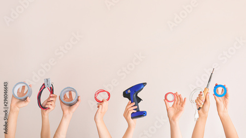 Female hands with electrician's tools on color background