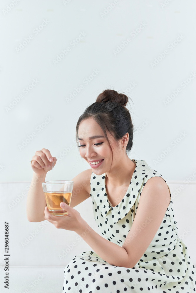 Happy asian woman sitting on her sofa holding cup at home Happy asian woman sitting on her sofa holding cup at home