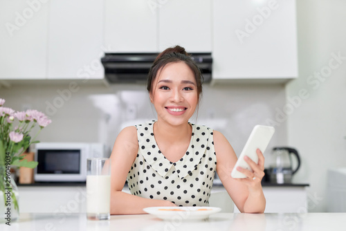young girl in the kitchen with the phone, breakfast with milk and cookies