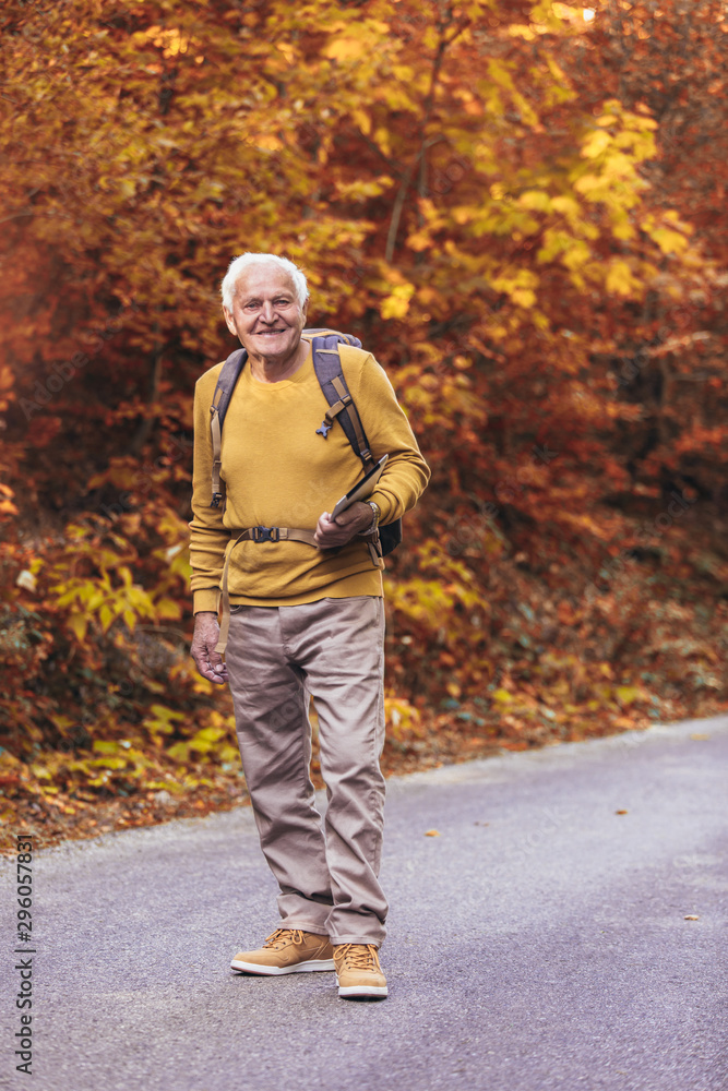 Obraz premium Senior man hiking in autumn forest.