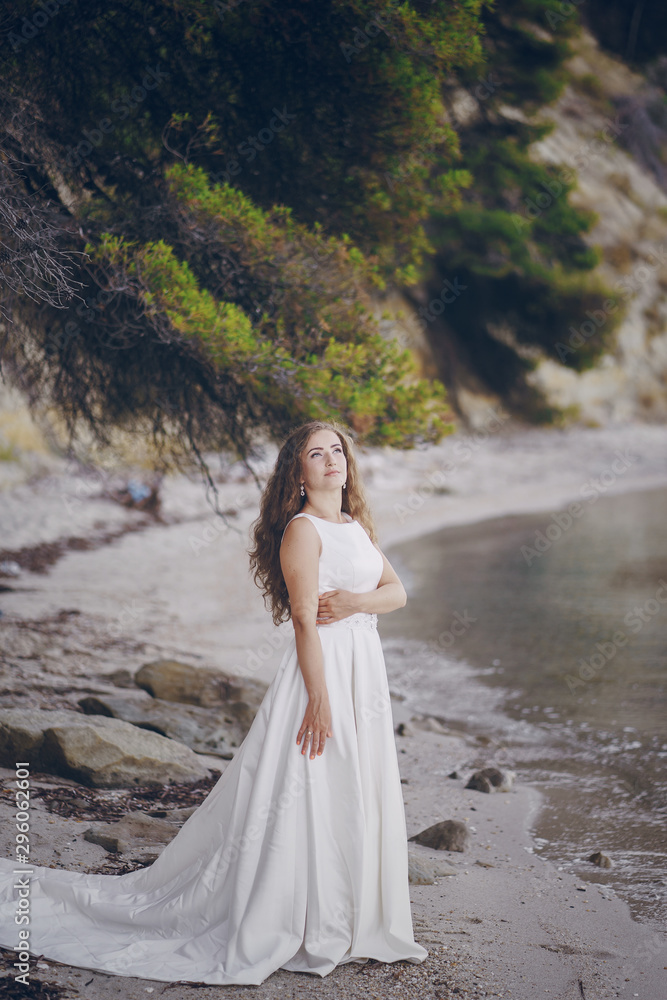 Beautiful long-haired bride in a magnificent white dress walking on a beach Beautiful long-haired bride in a magnificent white dress walking on a beach