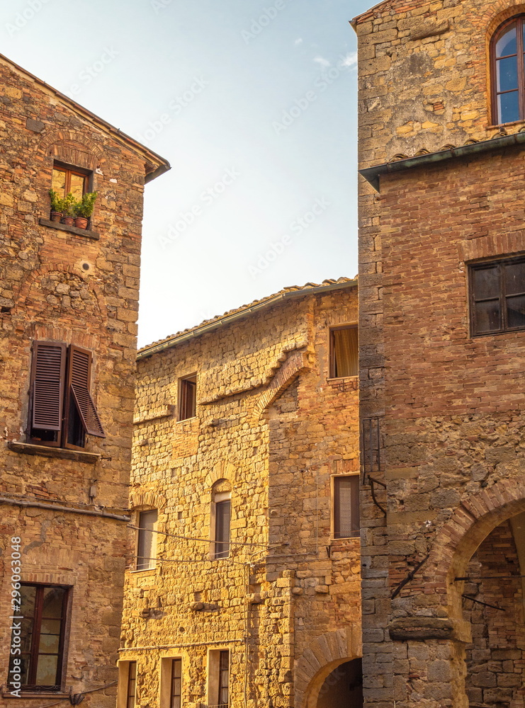 Narrow street with old stone houses in medieval city of Volterra Narrow street with old stone houses in medieval city of Volterra