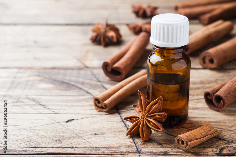 Essential aroma oil with cinnamon and star anise on wooden background. Selective focus. Essential aroma oil with cinnamon and star anise on wooden background. Selective focus.