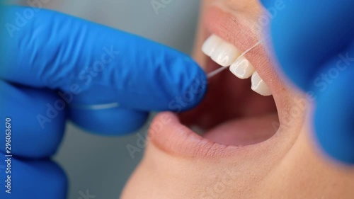 process of cleaning teeth with dental floss during dentist visit close up