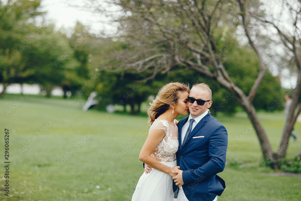 Beautiful bride in a long white dress. Handsome fiance in a blue suit. Couple in a summer park Beautiful bride in a long white dress. Handsome fiance in a blue suit. Couple in a summer park