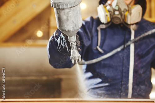 Close up image of carpenter painting with a paint spray gun