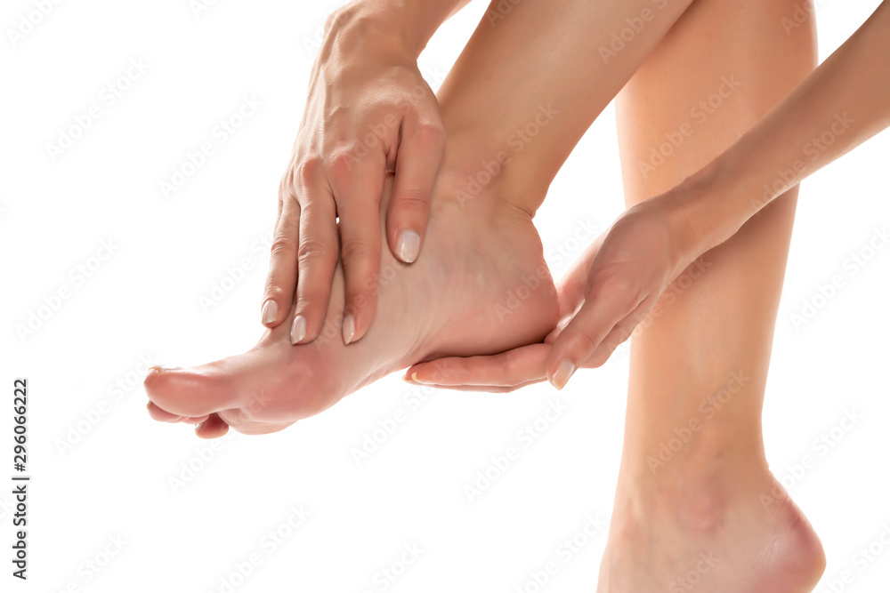 woman applying lotion on her feet on white background woman applying lotion on her feet on white background