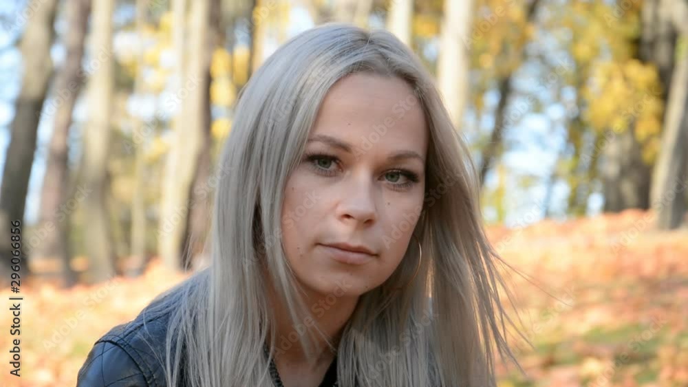 Outdoor portrait of a beautiful girl with white hair with a sad expression on the background of fallen leaves Outdoor portrait of a beautiful girl with white hair with a sad expression on the background of fallen leaves