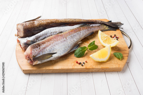 Raw fresh Pollock fish on a wooden Board with lemon
